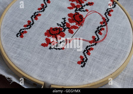 Handgemachte traditionelle Folk Kreuzstich Blumenmuster in den hölzernen Reifen auf dem Tisch Stockfoto