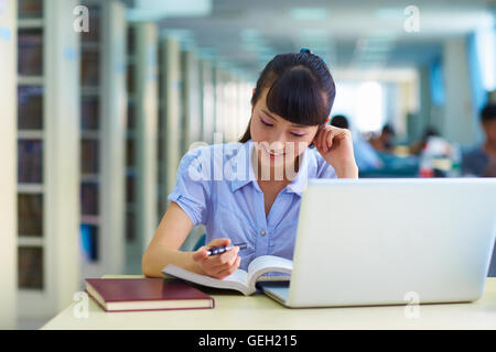 eine hübsche junge asiatische oder chinesischen College Student Studium in der Bibliothek Stockfoto
