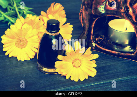 Calendula-Öl in eine Flasche aus Glas auf einem hölzernen Hintergrund. Vintage dunkel getönten-Effekt Stockfoto