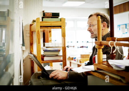 Ein Mann mit einem Laptop-Computer auf eine Buchbinderei-Geschäft. Stockfoto