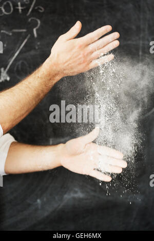 Nahaufnahme eines Bäckers stehen vor einer Tafel, seine Hände mit Mehl bestäuben. Stockfoto