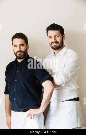 Halbe Länge Portrait von zwei bärtige Männer, weiße Schürzen tragen in die Kamera schaut. Stockfoto