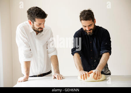 Zwei Bäcker an einem Tisch stehend, Brotteig kneten. Stockfoto