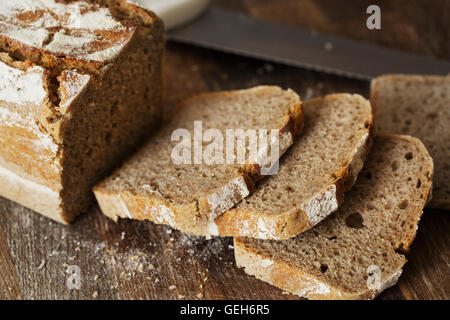 Nahaufnahme von einem Laib und frisch gebackenes Brot auf ein Schneidbrett aus Holz. Stockfoto