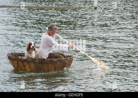 Mann und sein Hund in einem Coracle an an der Themse traditionellen Boat Festival, Fawley Wiesen, Henley On Thames, Oxfordshire, England Stockfoto