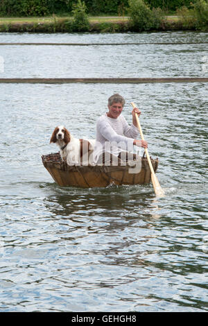 Mann und sein Hund in einem Coracle an an der Themse traditionellen Boat Festival, Fawley Wiesen, Henley On Thames, Oxfordshire, England Stockfoto