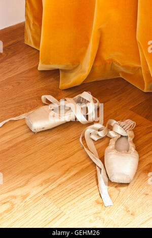 Ballett Spitzenschuhe auf dem Holzboden vor dem orange Vorhang Stockfoto