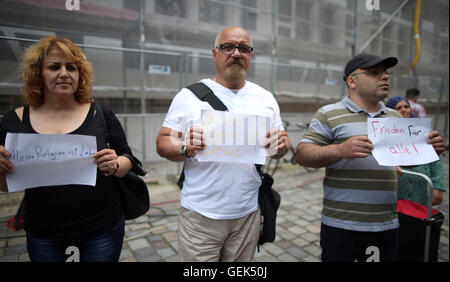 Ansbach, Deutschland. 26. Juli 2016. Flüchtlinge aus Syrien und dem Irak stehen nahe dem Aufstellungsort des Angriffs und Schilder geschrieben mit "Frieden für alle" und "meine Religion ist die Liebe" in Ansbach, Deutschland, 26. Juli 2016 halten. in einem mutmaßlichen islamistischen motivierten Angriff auf 24. Juli 2016 wurden 15 Menschen verletzt. Der mutmaßliche Täter, 27-Year-Old Flüchtling aus Syrien, wurde bei der Explosion getötet. Foto: DANIEL KARMANN/Dpa/Alamy Live News Stockfoto