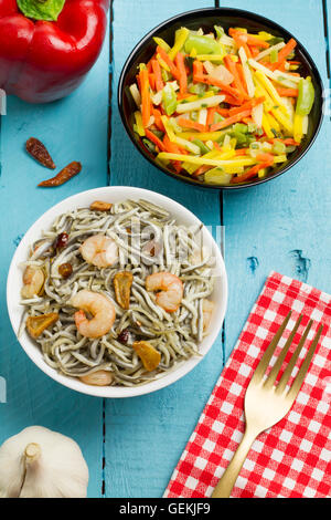 Surimi Glasaale mit Garnelen, Knoblauch und Pfeffer auf eine schwarze Schale mit einigen Zutaten auf einem Holztisch Stockfoto