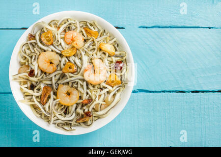 Surimi Glasaale mit Garnelen, Knoblauch und Pfeffer auf einem blauen Holztisch Stockfoto