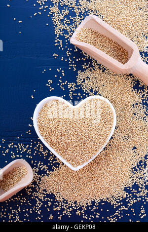 Ich liebe Quinoa-Konzept mit weißer Maserung Quinoa in weiße Herzförmige Schüssel auf einem dunkelblauen Hintergrund Holz. Stockfoto