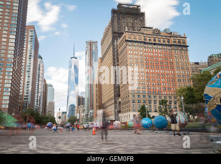 Langzeitbelichtung Schuß über Batterie Platz in Richtung One World Trade Center und der Whitehall Building mit Bewegung verwischt Menschen Stockfoto