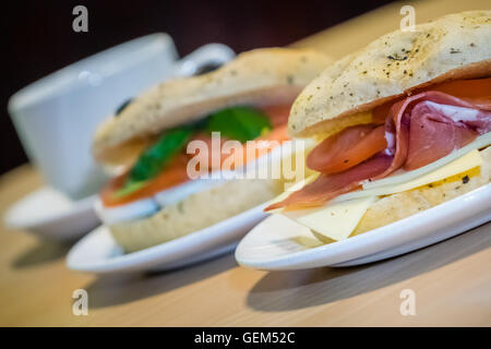 Frühstück Brötchen auf einem Teller, gefüllt mit Cheddar-Käse, Schinken und Tomaten Stockfoto