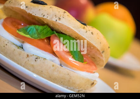 Frühstück Brötchen auf einem Teller, gefüllt mit Mozzarella, Tomaten und Basilikum Stockfoto