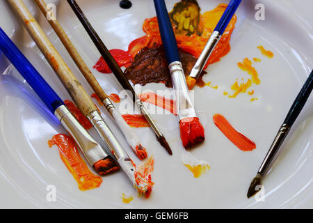 Pinsel und Farben auf einem weißen Teller Stockfoto
