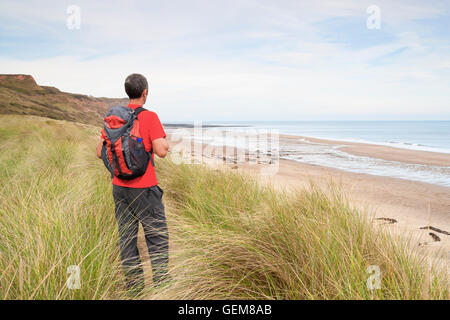 Männliche Wanderer auf Cleveland Weise Küstenweg mit Blick auf Cattersty Sand-Strand in Skinningrove, North Yorkshire, England. UK Stockfoto