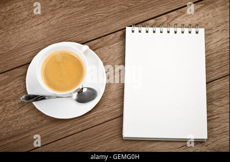 Ansicht von oben Tasse Kaffee in eine weiße Tasse und Spiral-Notizblock auf hölzernen Hintergrund Stockfoto