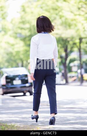 Business-Frau zu Fuß zusammen mit Bäumen gesäumten Straße Stockfoto