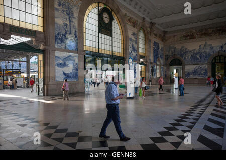 Reisende fahren Sie unter traditionellen Azulejo-Fliesen im Inneren reich verzierten Sao Bento Bahnhof in Porto, Portugal. Stockfoto