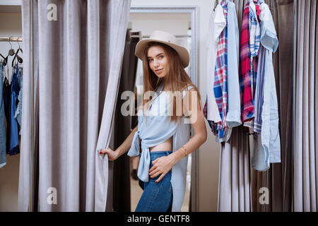 Schöne junge Frau, die versucht auf der Kleidung in der Anprobe der Kleidung shop Stockfoto