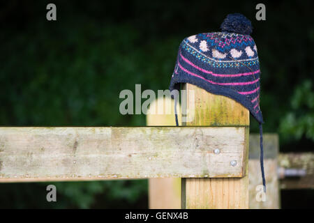 Verlorene Mütze auf hölzernen Zaunpfosten. Wolligen Kind Hut verlegt auf Land platziert auf Tor in der Hoffnung auf Gesehenwerden durch Eigentümer Stockfoto