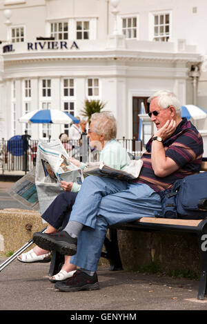 Großbritannien, England, Devon, Sidmouth, The Esplanade, älteres Ehepaar Zeitungslektüre bei Sonnenschein Stockfoto