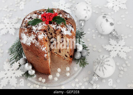 Schokolade Panettone Weihnachtskuchen mit Beeren der Stechpalme, weißen und silbernen Schneeflocke und Christbaumkugel Dekorationen. Stockfoto