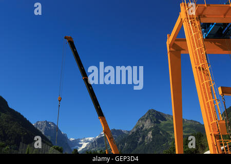 Ein Foto von zwei Baukräne auf einer großen Baustelle in der alpinen Region der Schweiz. Stockfoto