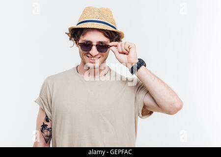 Porträt eines lächelnden jungen Mannes mit Hut seine Brille abnehmen Stockfoto