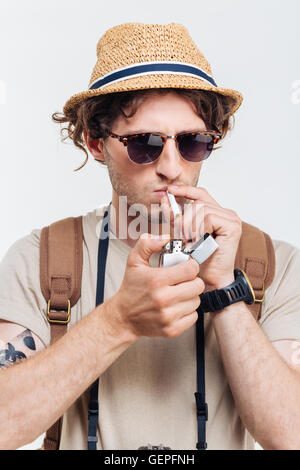 Stilvolle Jüngling mit Retro-Kamera qualmender Zigarette isoliert auf weißem Hintergrund Stockfoto