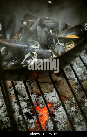 Nahaufnahme von einer Pfanne schwarz Muscheln bei einem Holzkohlegrill. Stockfoto