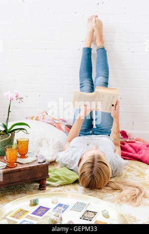 Eine junge Frau in Jeans Lyng auf dem Rücken mit den Beinen gegen die Wand. Stockfoto