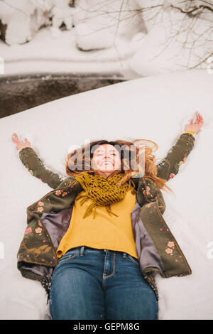 Eine Frau liegt auf einer Schneewehe Arme ausgestreckt. Stockfoto