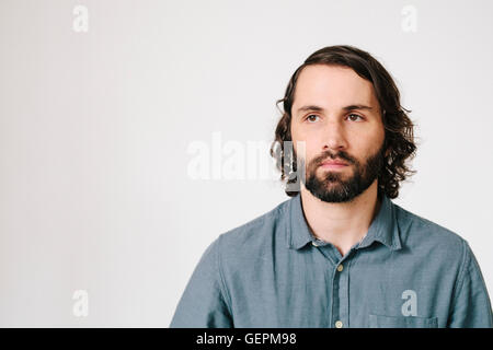 Ein junger Mann mit einem Bart und schwarzen Haaren in ein blaues Hemd. Stockfoto