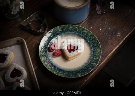 Valentinstag Backen, hoher Winkel Ansicht einer Platte mit Herz geformte Gebäck und frischen Himbeeren. Stockfoto