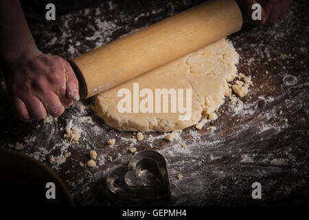 Valentinstag Backen, Frau Teig mit einem Nudelholz ausrollen. Stockfoto