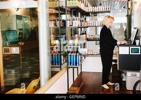 Eine Frau mit Hilfe eines Laptops in einem Friseursalon, Verwaltung und Führung des Unternehmens. Stockfoto