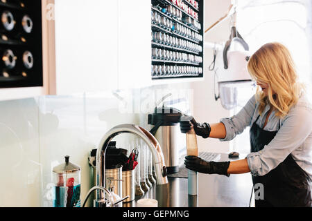 Eine Frau mit Handschuhen arbeiten Reinigungsgeräte in einem Friseursalon. Stockfoto