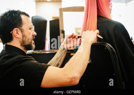 Ein Friseur mit einem Kunden, ihr langes glattes Haar schneiden schneiden die Enden. Stockfoto