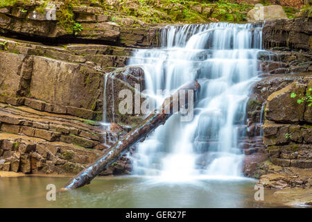 Kleiner Wasserfall im Bergwald mit seidig schäumenden Wasser Stockfoto