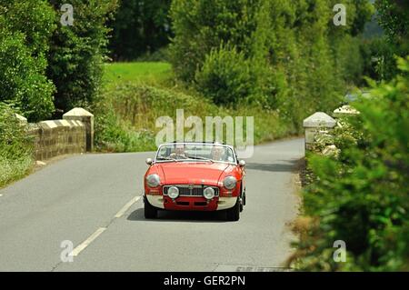 MGB GT Roadster eine Steinbrücke überqueren, auf einer Landstraße auf einen Sommer-Oldtimer-Rallye in England Stockfoto