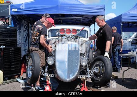 Mechanik, die Arbeit an einem Hot Rod Dragster bei einem Rennen treffen auf Santa Pod an einem heißen Sommertag Stockfoto