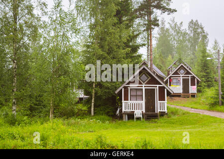 Sommer-outdoor-Aktivitäten, skandinavischen Urlaub. Kleine Holzhäuser camping unter den Sommerregen auf der grünen Wiese. Finnland Stockfoto