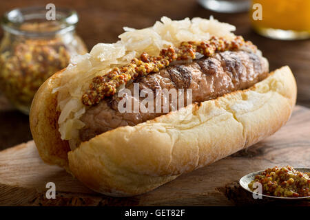 Eine leckere Bratwürste mit Sauerkraut und groben Senf auf einem getoastete Hotdog-Brötchen. Stockfoto