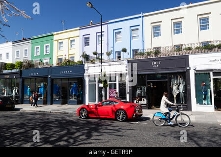 Ein roter Ferrari vor Boutiquen auf Westbourne Grove in Notting Hill geparkt. Stockfoto