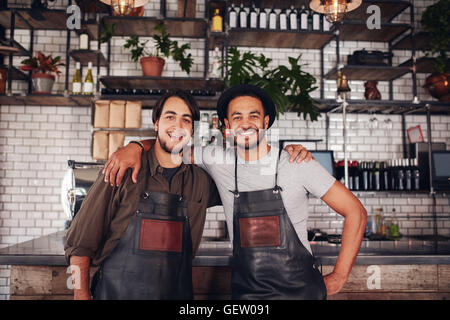 Porträt von zwei jungen Coffee-Shop-Partner zusammen an der Theke stehen. Glückliche junge männliche Barkeeper. Stockfoto