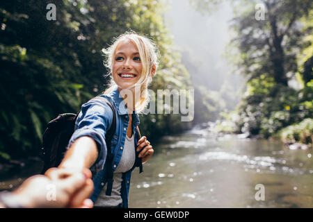 Wanderer-Frau hält die Hand des Menschen und führt ihn auf die Natur im Freien. Paar in der Liebe. Point Of View erschossen. Stockfoto