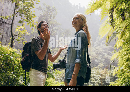 Aufnahme des jungen Mann und Frau stehen auf Bergweg und genießen den Regen. Ein paar Wanderungen in der Natur mit Rucksack und Kamera. Stockfoto