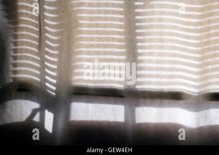 Horizontal-Jalousien werfen eine Muster von Schatten auf eine transparente Baumwolle Vorhang. Stockfoto