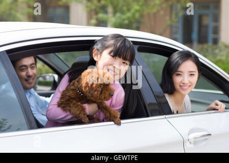 Glückliche junge chinesische Familie mit ihrem Hund im Auto sitzen Stockfoto